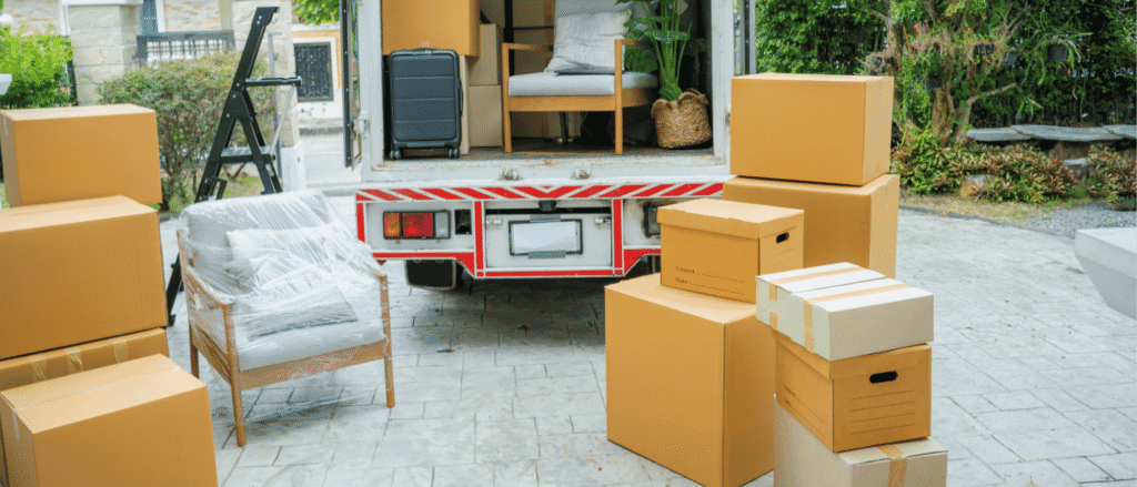 Moving boxes and furniture beside a moving truck, a reminder to update your estate plan after moving to Utah
