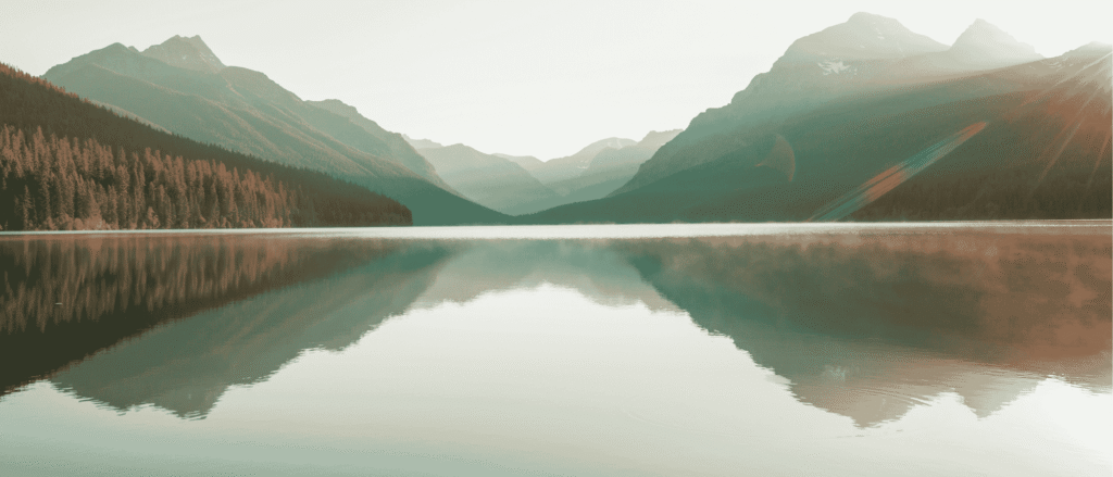 Mountains reflected in a calm lake, suggesting a steady perspective during market volatility