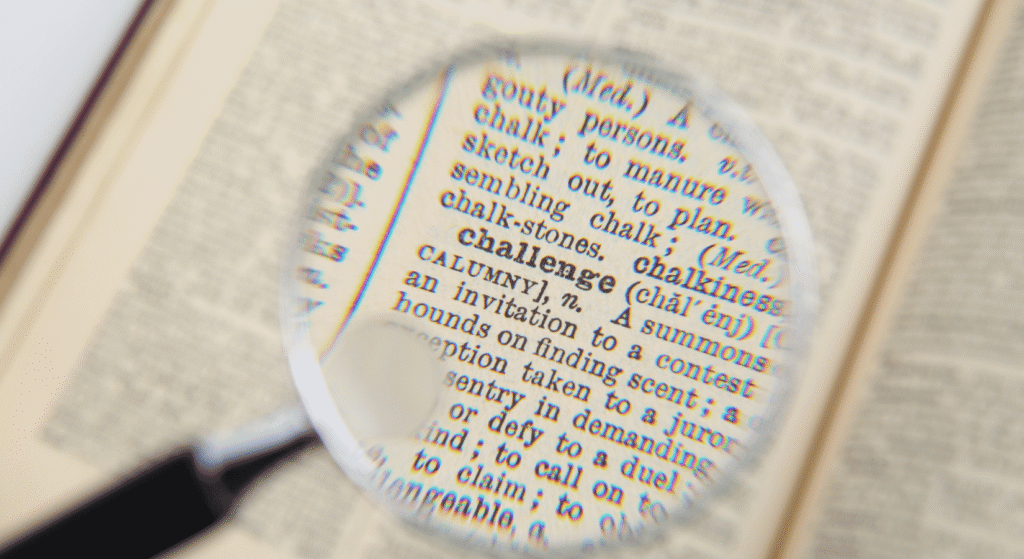 A magnifying glass over the word challenge in a dictionary, representing a closer look at an existing estate plan