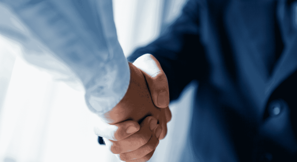 Two business partners shaking hands, a reminder that co-owners should agree on a buyout plan in advance