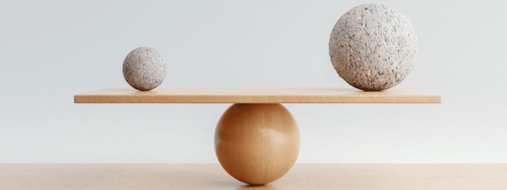 Two stones balanced on a wooden seesaw, illustrating the balance between risk tolerance and risk capacity