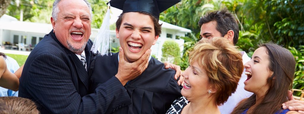 College graduate in a cap and gown hugging a proud grandparent on graduation day