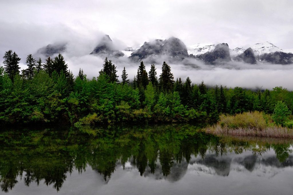 Misty mountains reflected in a calm lake, illustrating strong markets alongside lingering uncertainty in May 2026